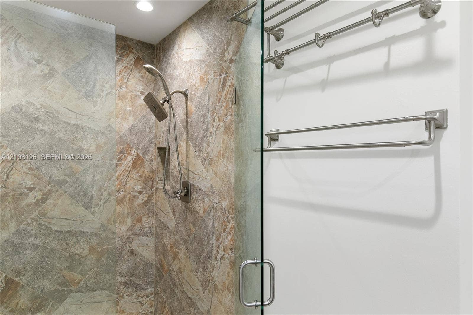 11700 NW 4th Street, Plantation, Plantation, FL 33325 Walk-in shower featuring large-format tile surround, adjustable handheld shower fixture, built-in recessed storage niche, frameless glass door, and brushed nickel hardware