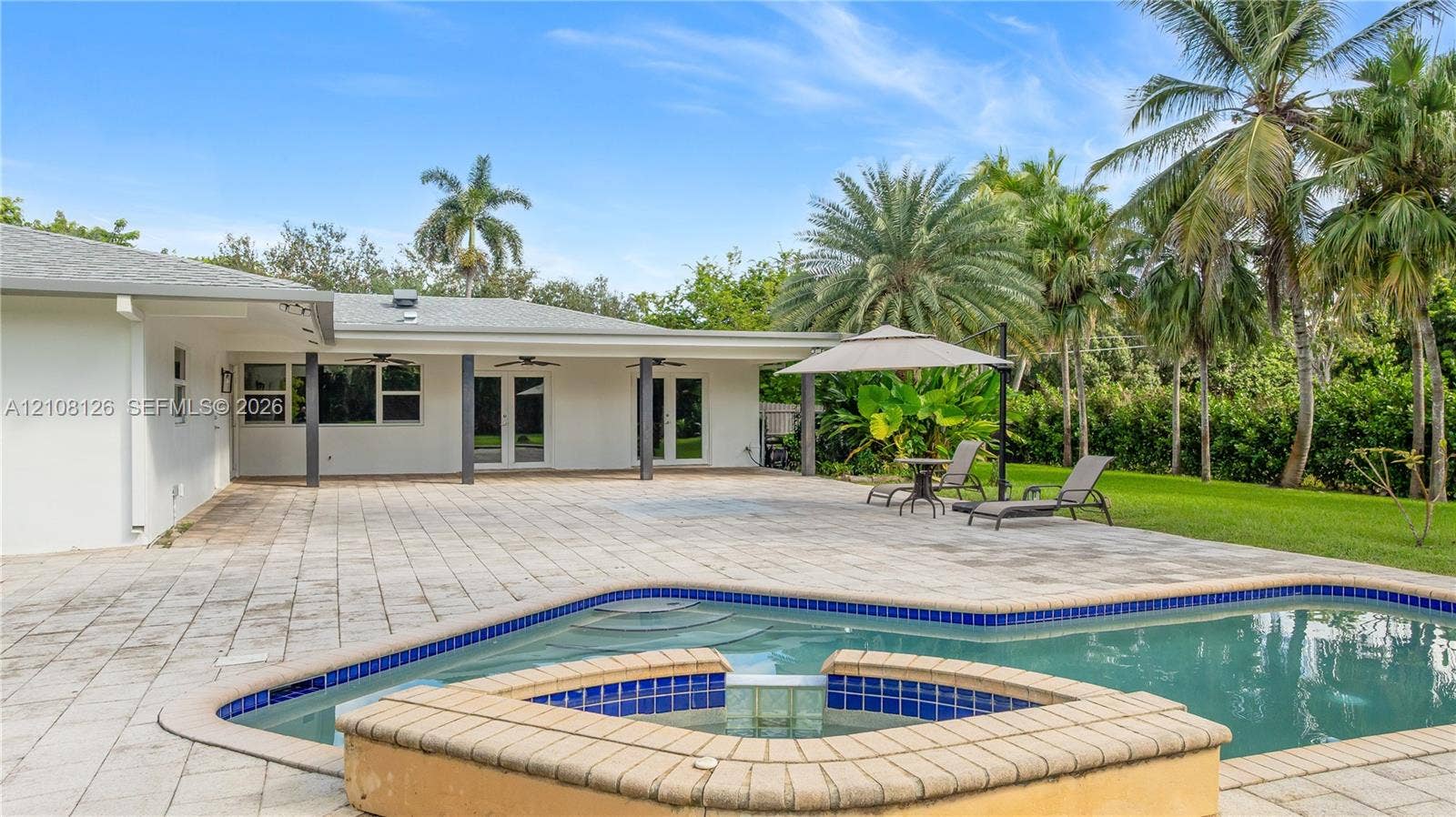 11700 NW 4th Street, Plantation, Plantation, FL 33325 Backyard featuring a paved stone patio, an in-ground swimming pool, a raised tile-accented spa, and a covered lanai