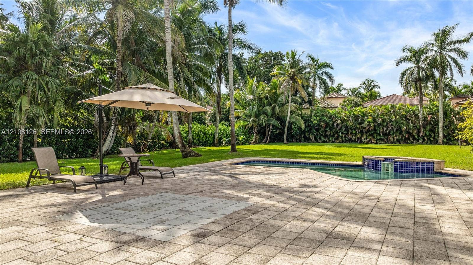 11700 NW 4th Street, Plantation, Plantation, FL 33325 Expansive backyard featuring a stone-paver patio, swimming pool, raised tiled spa, manicured lawn, and mature palm trees
