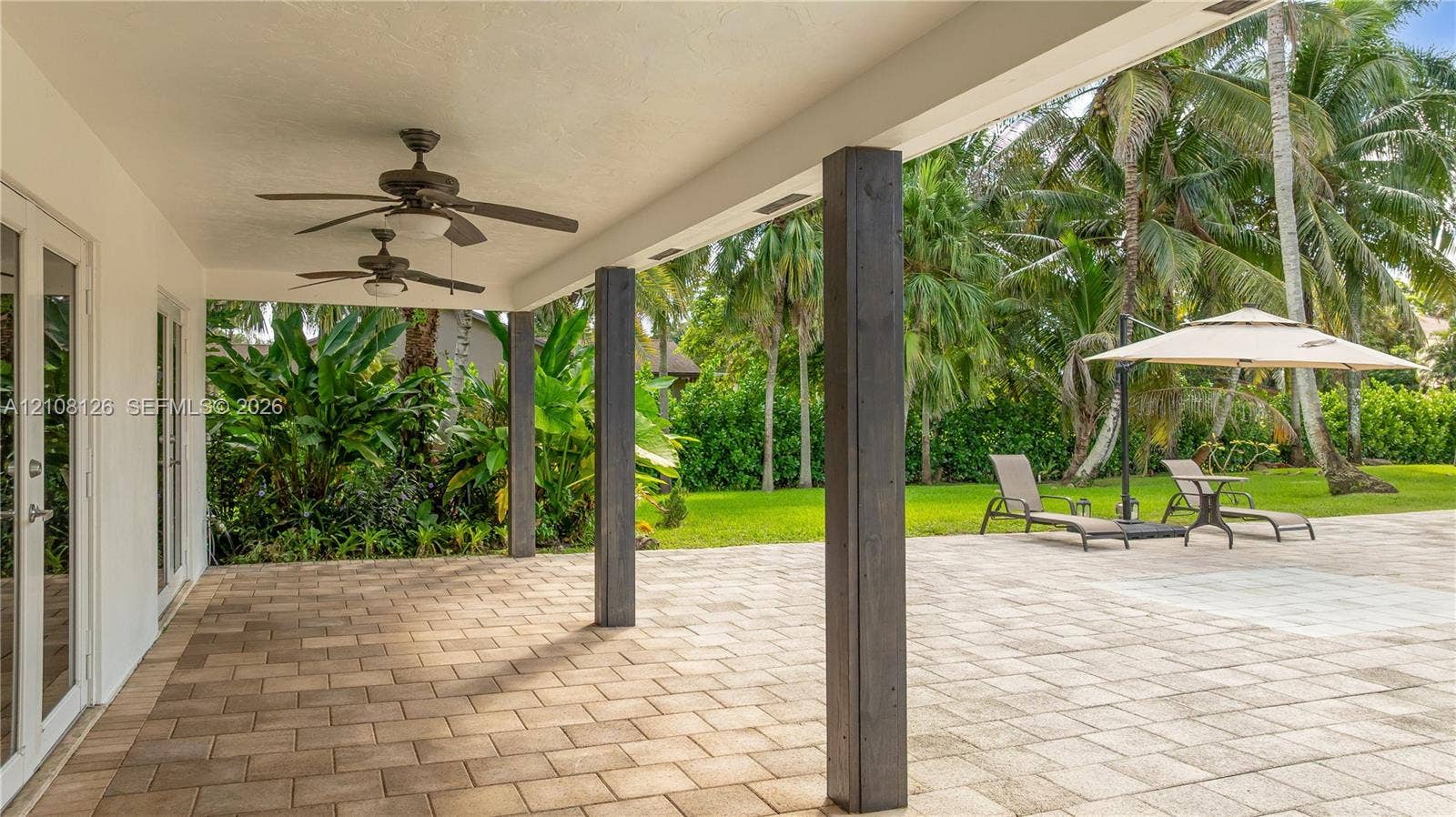 11700 NW 4th Street, Plantation, Plantation, FL 33325 Covered patio featuring concrete paver flooring, dual ceiling fans, and dark-stained structural support pillars