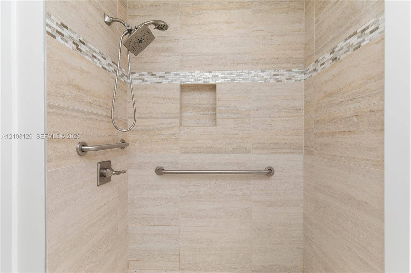 11700 NW 4th Street, Plantation, Plantation, FL 33325 Walk-in shower featuring neutral stone-finish tile surround, integrated mosaic accent banding, built-in recessed niche, handheld shower fixture, and brushed nickel hardware