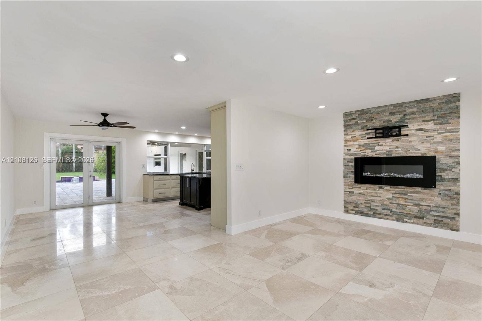 11700 NW 4th Street, Plantation, Plantation, FL 33325 Living area featuring large-format tile flooring, recessed lighting, and a floor-to-ceiling stone-veneer accent wall with an integrated electric fireplace