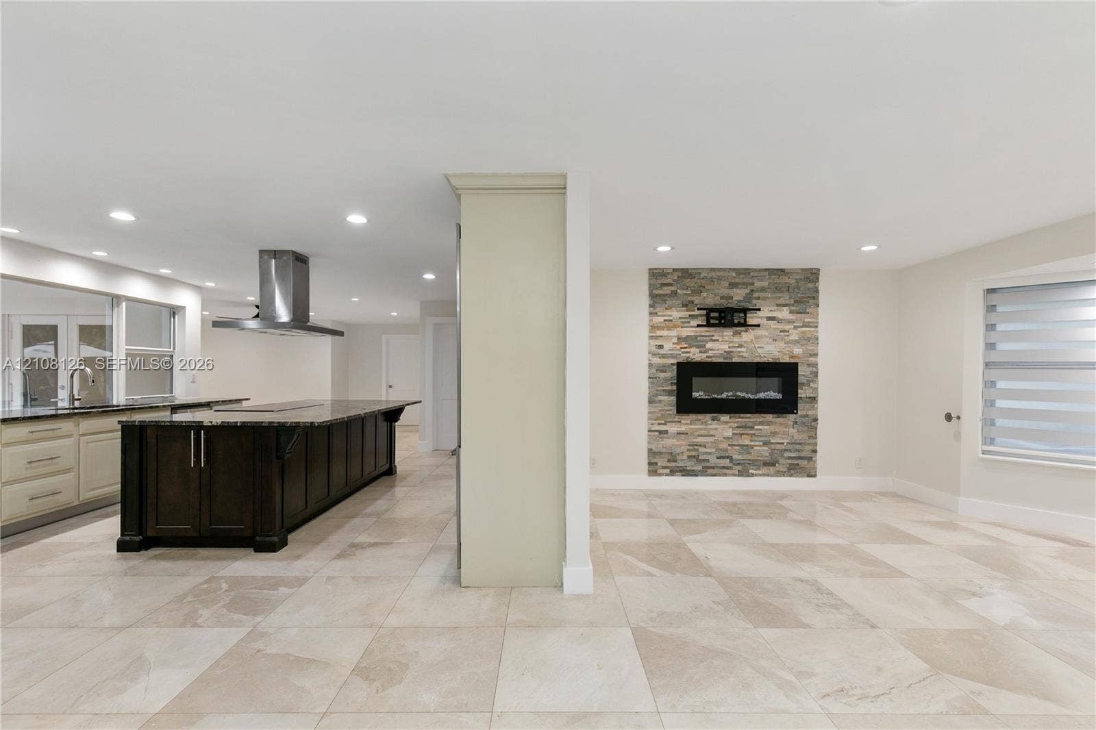 11700 NW 4th Street, Plantation, Plantation, FL 33325 Kitchen featuring a dark-finish island with a countertop, stainless steel range hood, stone-finish fireplace, and neutral-tone tile flooring