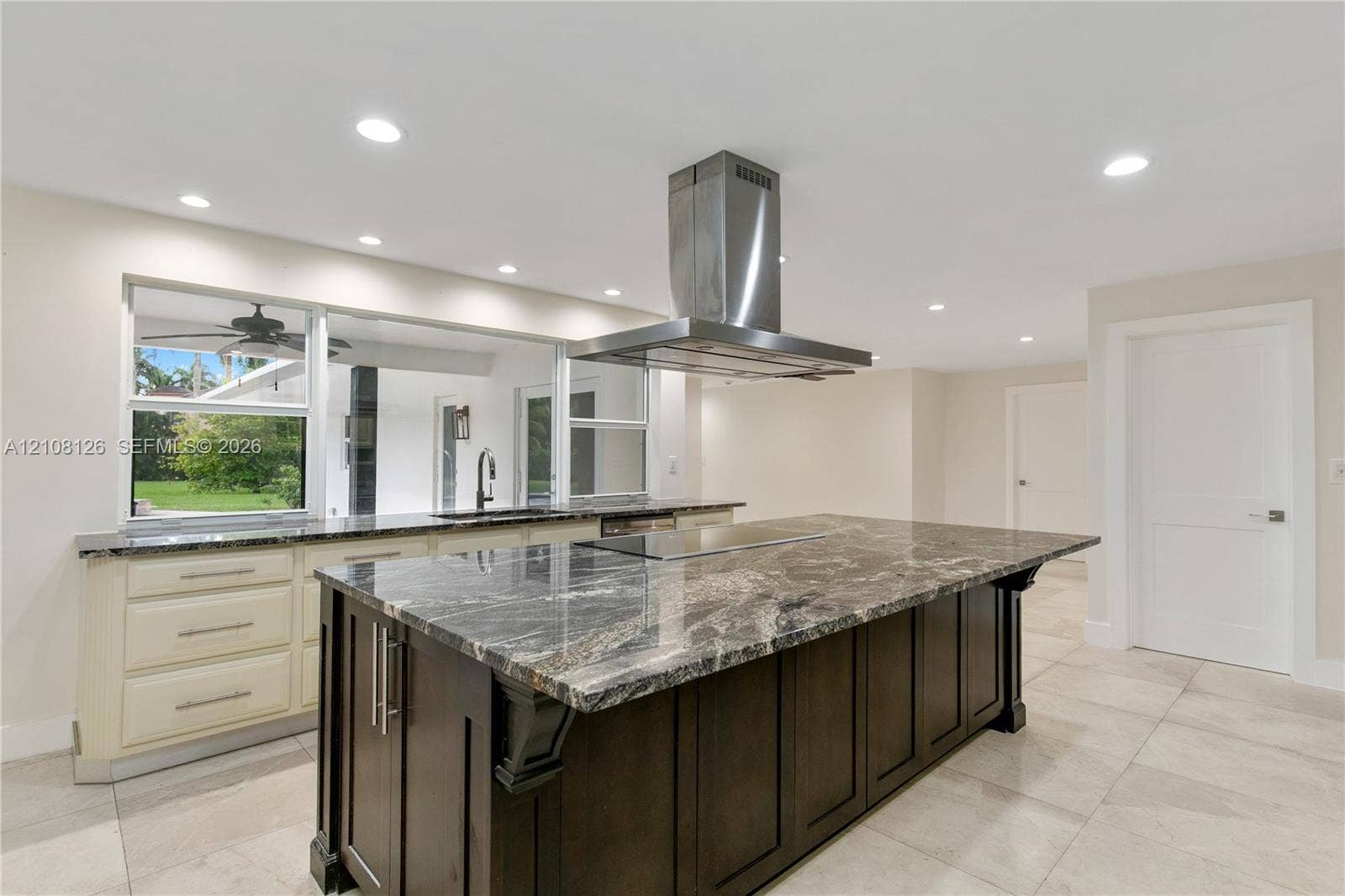 11700 NW 4th Street, Plantation, Plantation, FL 33325 Kitchen featuring a large central island with dark cabinetry and stone-finish countertop, stainless steel ceiling-mounted range hood, light-colored perimeter cabinetry, and large-format tile flooring