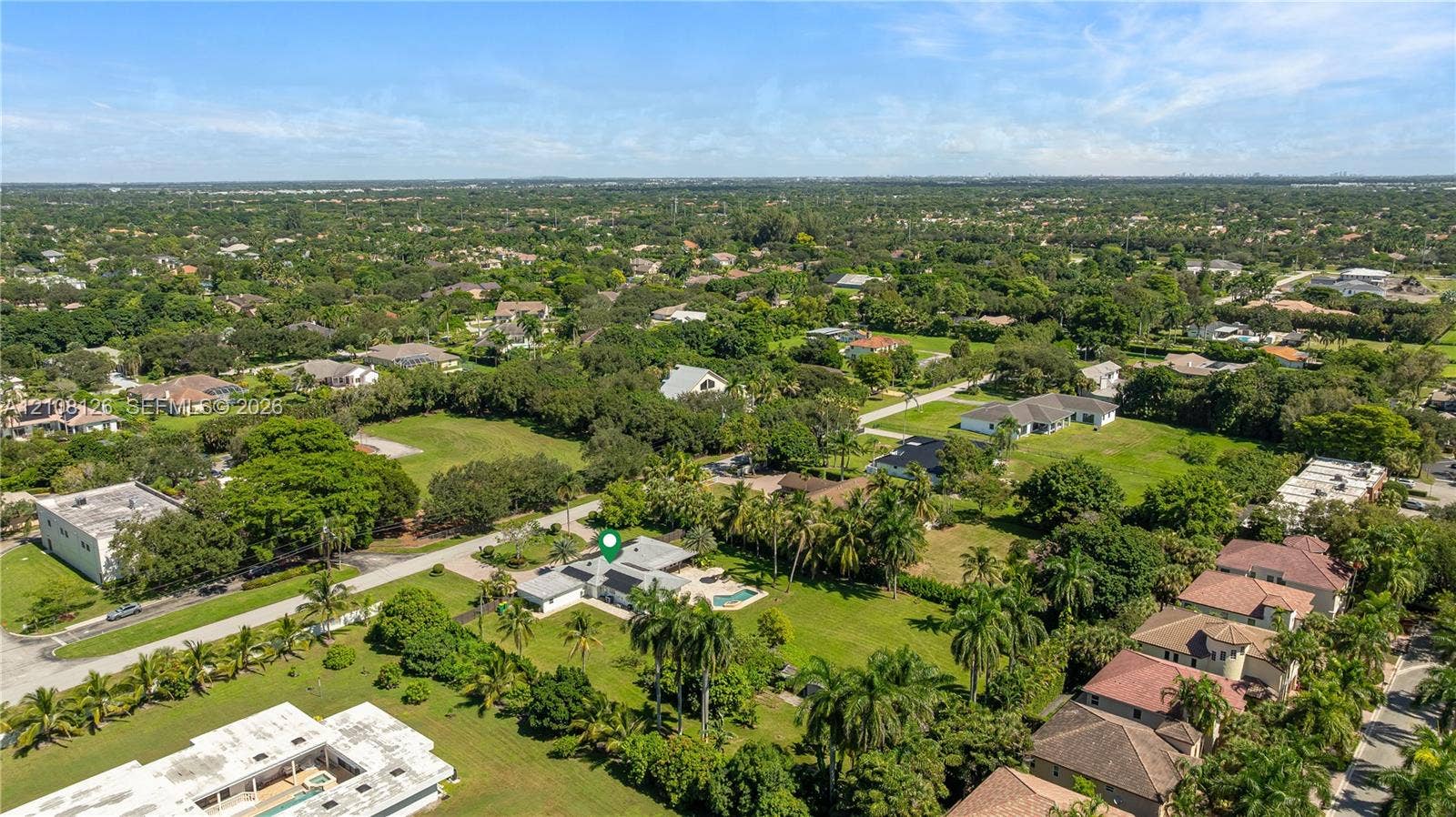 11700 NW 4th Street, Plantation, Plantation, FL 33325 Aerial perspective featuring a sprawling lot with an inground pool, expansive lawn, mature palms, and paved driveway access