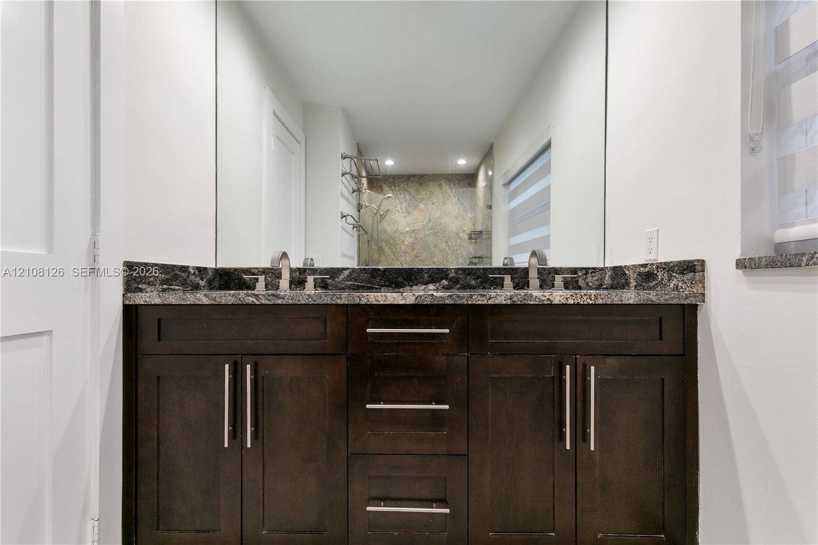11700 NW 4th Street, Plantation, Plantation, FL 33325 Dark-stained wood cabinetry featuring brushed nickel hardware, expansive vanity mirror, stone countertop, and dual under-mount sinks