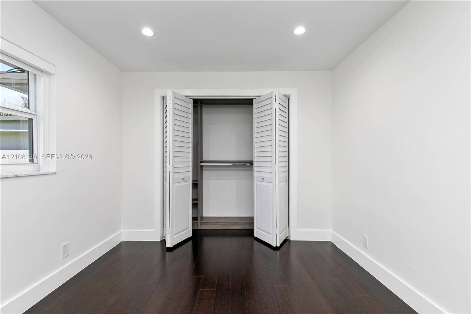 11700 NW 4th Street, Plantation, Plantation, FL 33325 Neutral interior featuring dark wood-finish flooring, recessed lighting, and a closet with white louvered bi-fold doors and built-in shelving