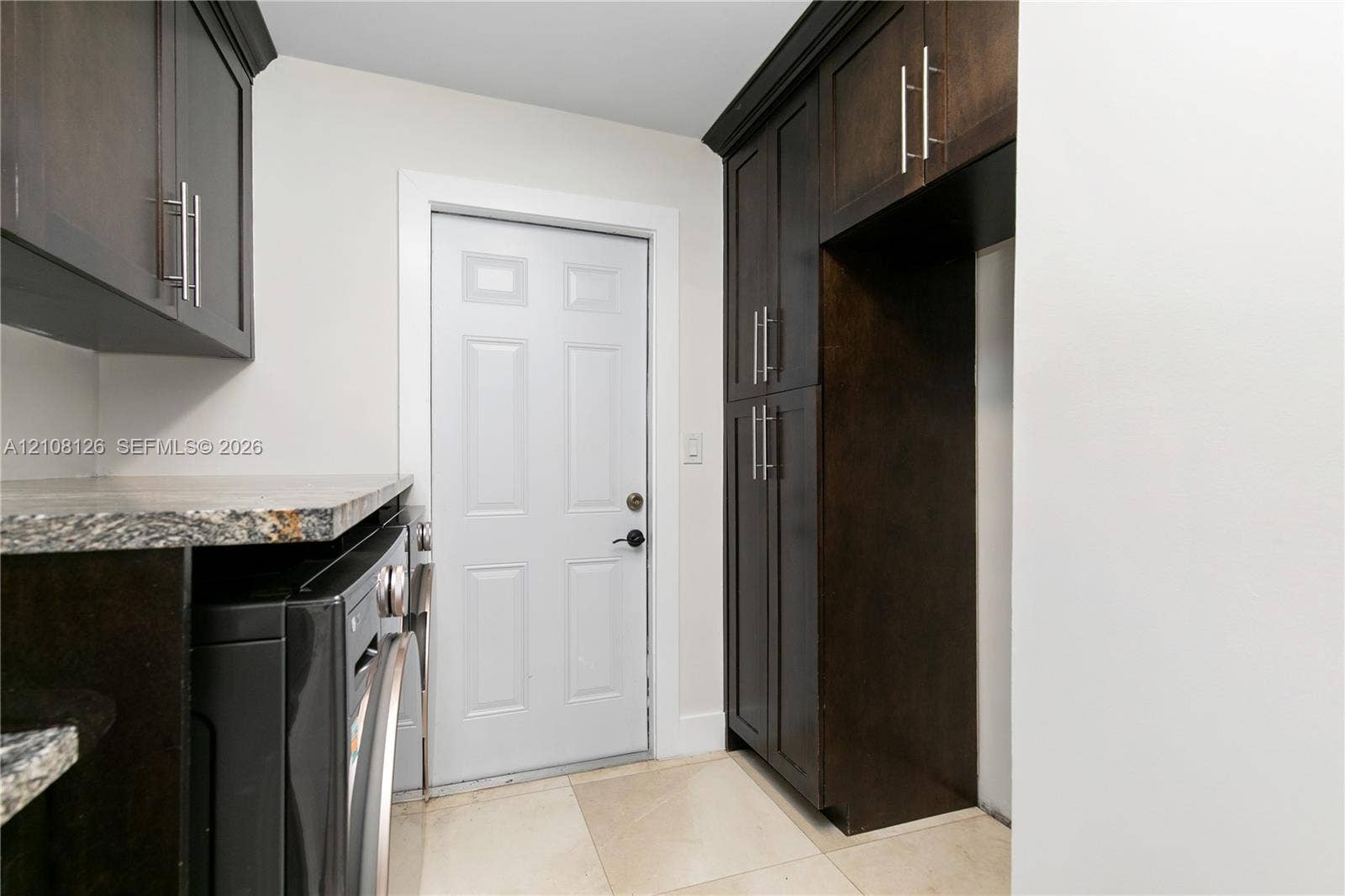11700 NW 4th Street, Plantation, Plantation, FL 33325 Dark-toned cabinetry featuring stainless steel hardware, stone-finish countertops, tile flooring, and a paneled exterior door