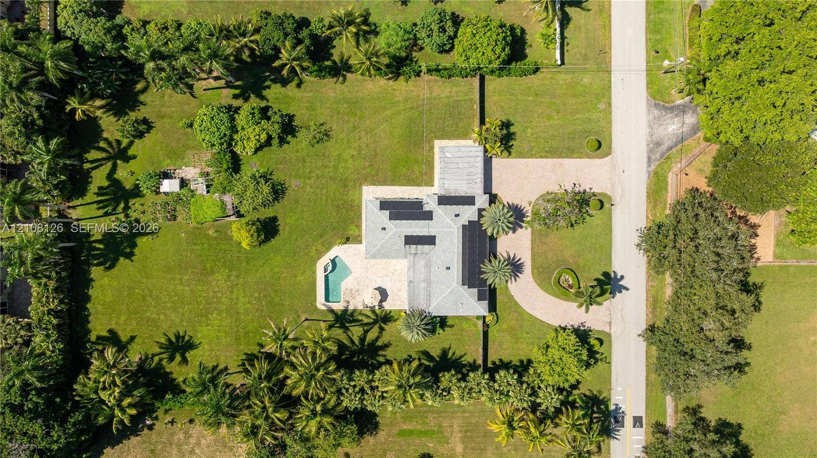 11700 NW 4th Street, Plantation, Plantation, FL 33325 Aerial perspective featuring an expansive lot, a private swimming pool, solar panels, and a paved circular driveway