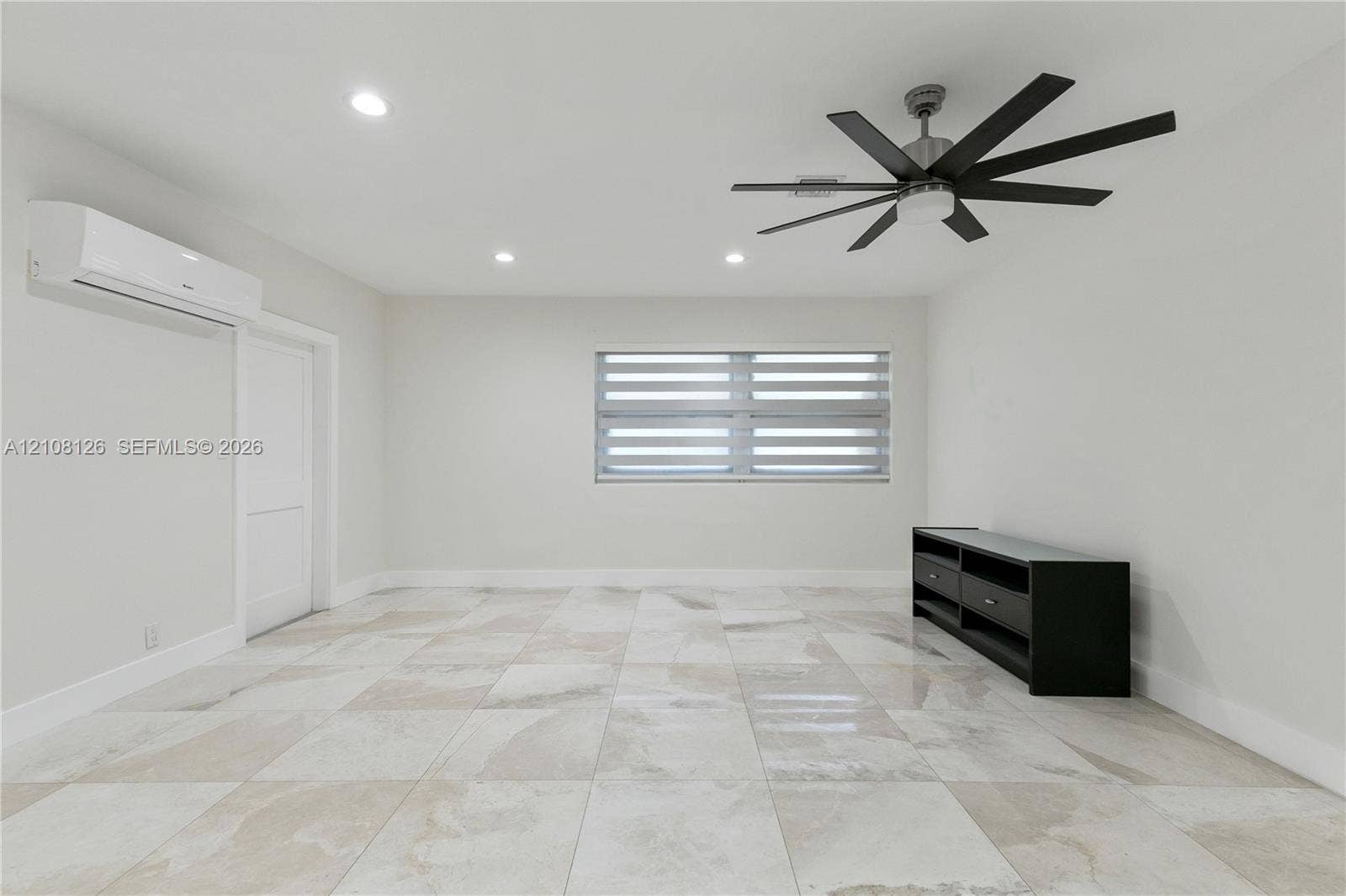 11700 NW 4th Street, Plantation, Plantation, FL 33325 Interior space featuring large-format stone-finish floor tiling, recessed lighting, a multi-blade ceiling fan, a wall-mounted ductless climate control unit, and window blinds