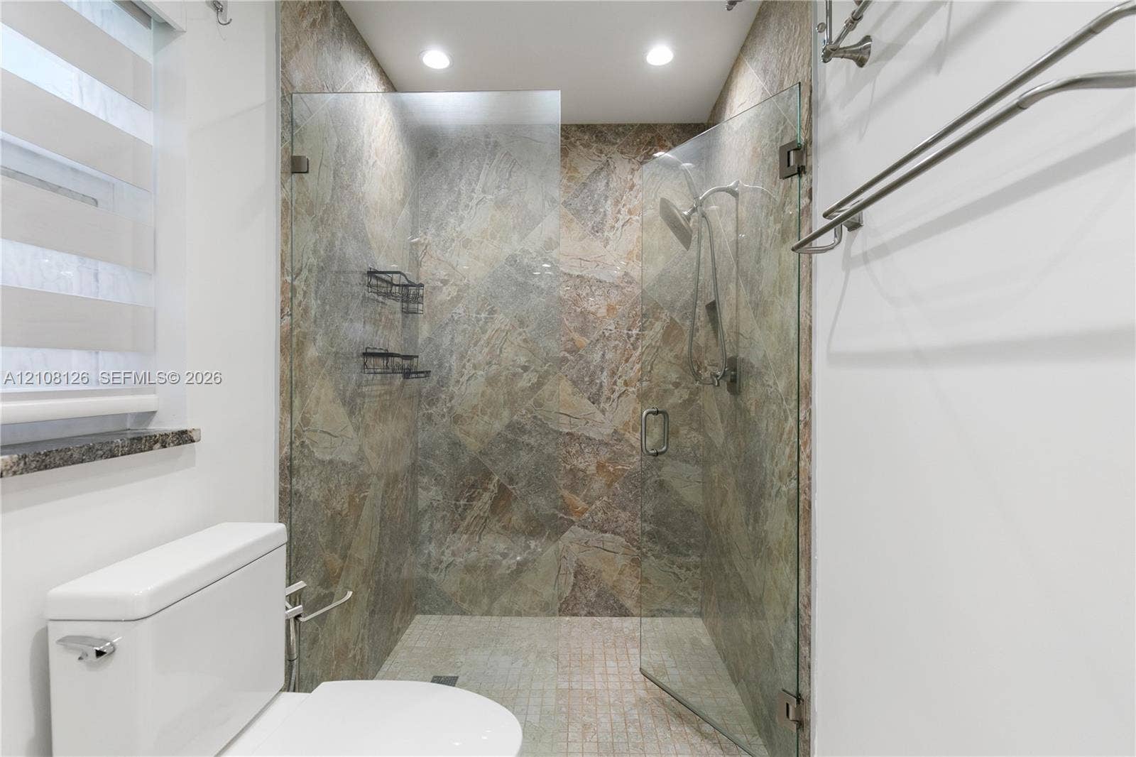 11700 NW 4th Street, Plantation, Plantation, FL 33325 Walk-in shower featuring natural-stone tile surround, frameless glass enclosure, handheld shower fixture, and recessed lighting