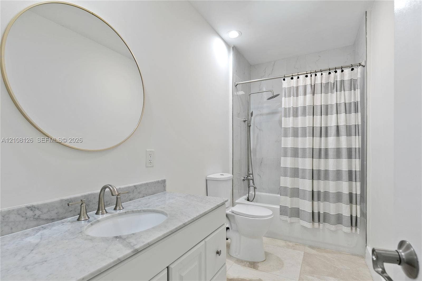 11700 NW 4th Street, Plantation, Plantation, FL 33325 Bathroom featuring a vanity with natural stone countertop, undermount sink, circular wall mirror, and a tub-shower combination with floor-to-ceiling tile surround