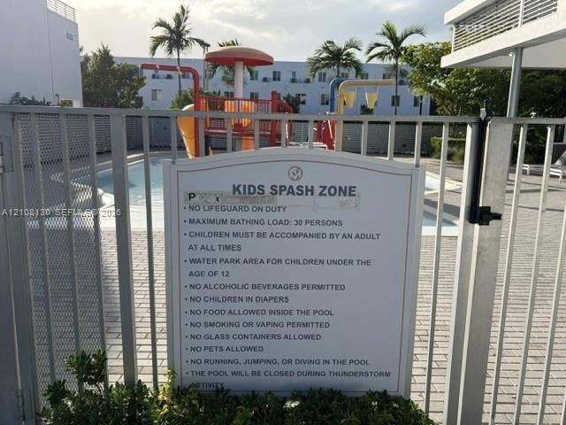 Outdoor water recreation area featuring a swimming pool, integrated splash pad, and perimeter metal fencing