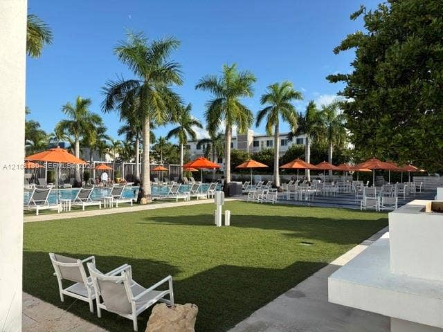 Outdoor recreation area featuring a swimming pool, synthetic turf lawn, stone hardscaping, and mature palm trees