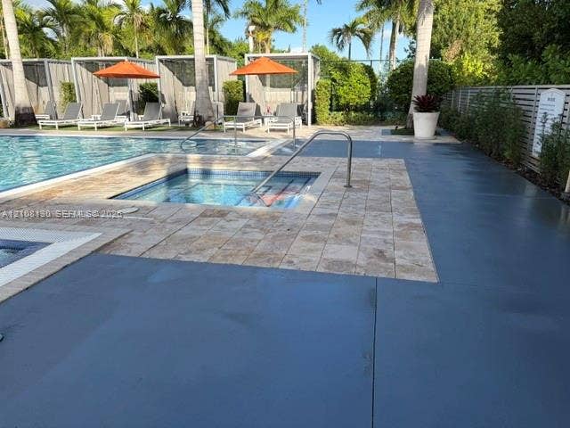Swimming pool with integrated spa, stone-paver decking, and metal-framed poolside cabanas