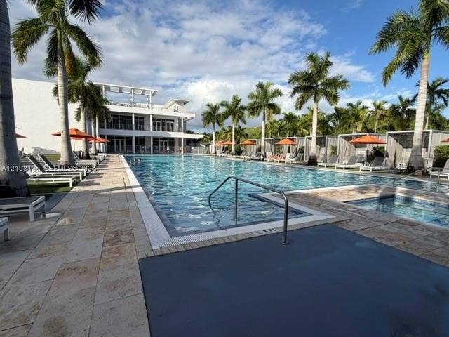 Large swimming pool with stone-tiled decking, attached spa, and metal-framed cabanas surrounded by mature palm trees