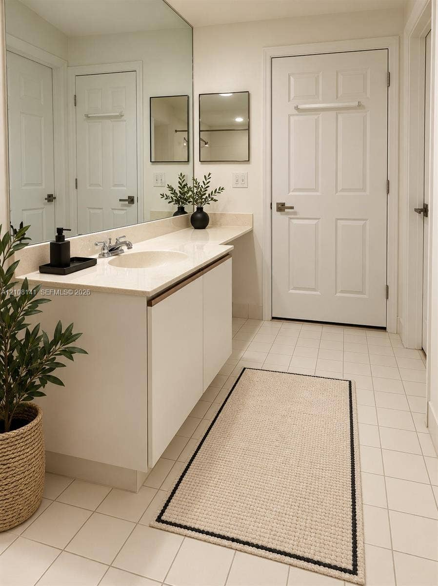 3135 NE 184th Street, #2205, Aventura, FL 33160 Bathroom vanity featuring a solid surface countertop, an integrated sink, flat-panel cabinetry, a full-width wall mirror, and ceramic tile flooring