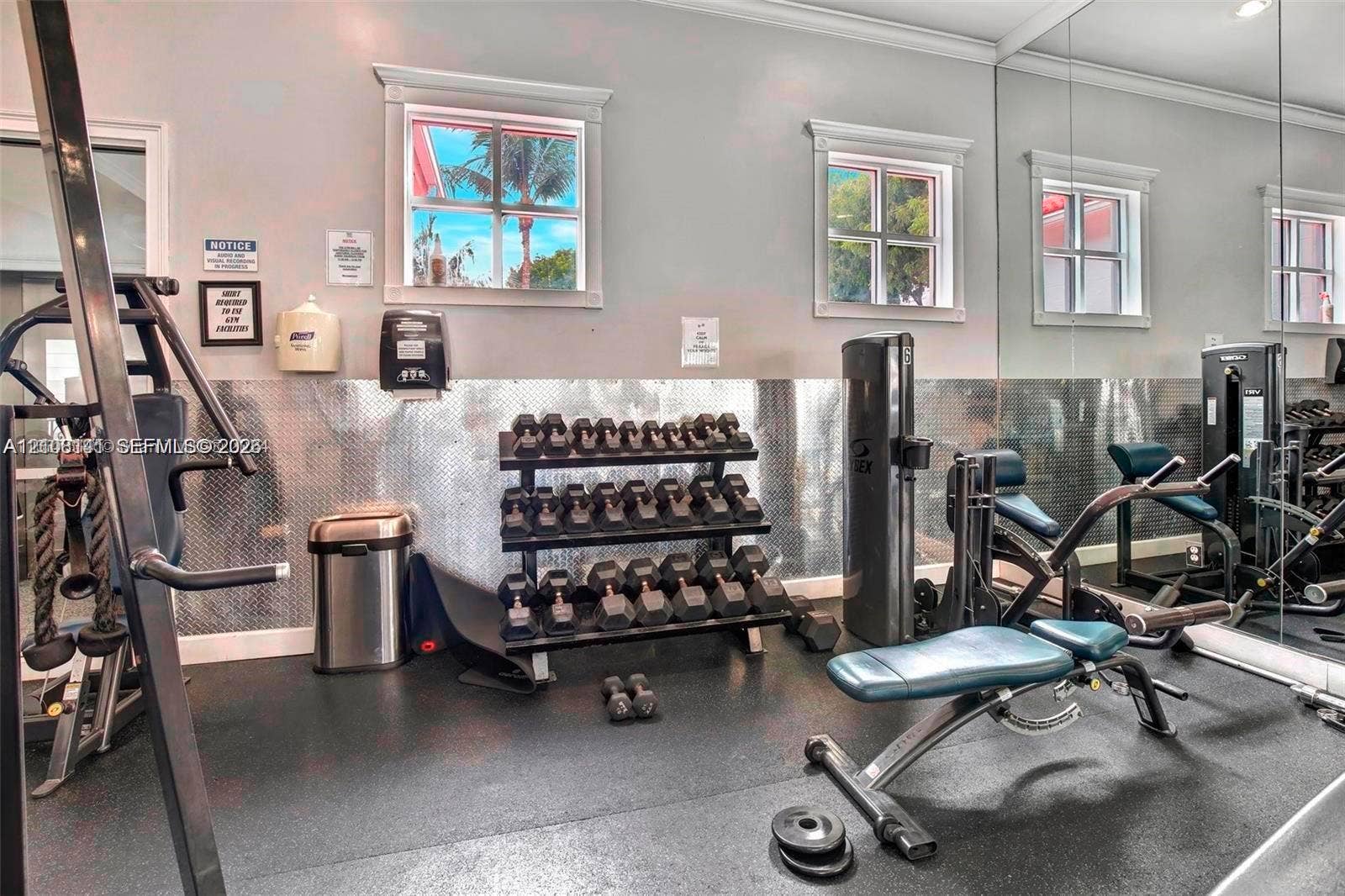3135 NE 184th Street, #2205, Aventura, FL 33160 Fitness space featuring rubber flooring, floor-to-ceiling mirrored walls, diamond-plate metal wall paneling, and multi-pane windows with trim casing