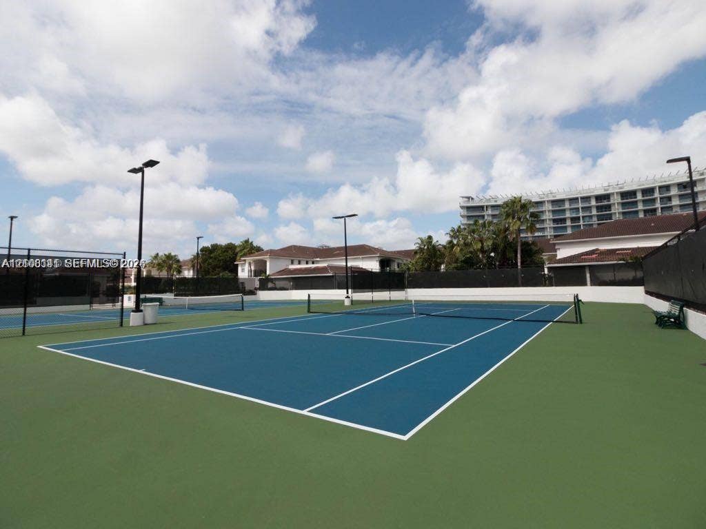 3135 NE 184th Street, #2205, Aventura, FL 33160 Hard-surface tennis courts featuring high-pole lighting, perimeter fencing, and dual-tone blue and green court surfacing