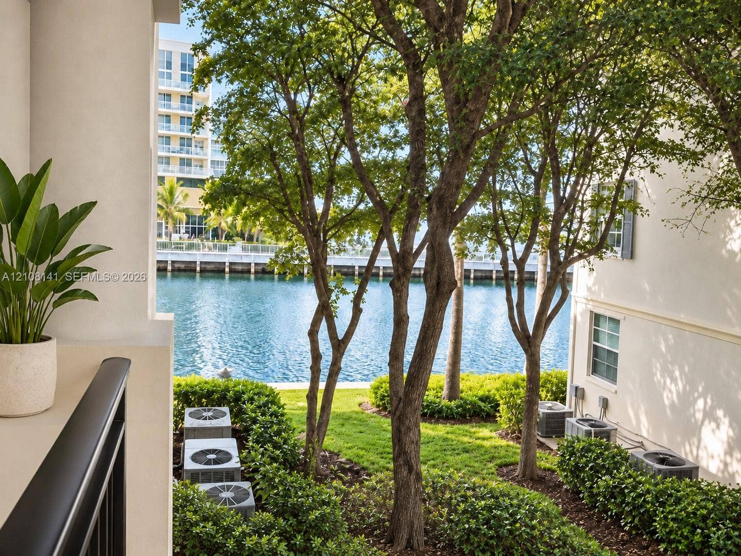 3135 NE 184th Street, #2205, Aventura, FL 33160 Covered terrace overlooking the intracoastal with mature trees, manicured landscaping, and a black metal railing