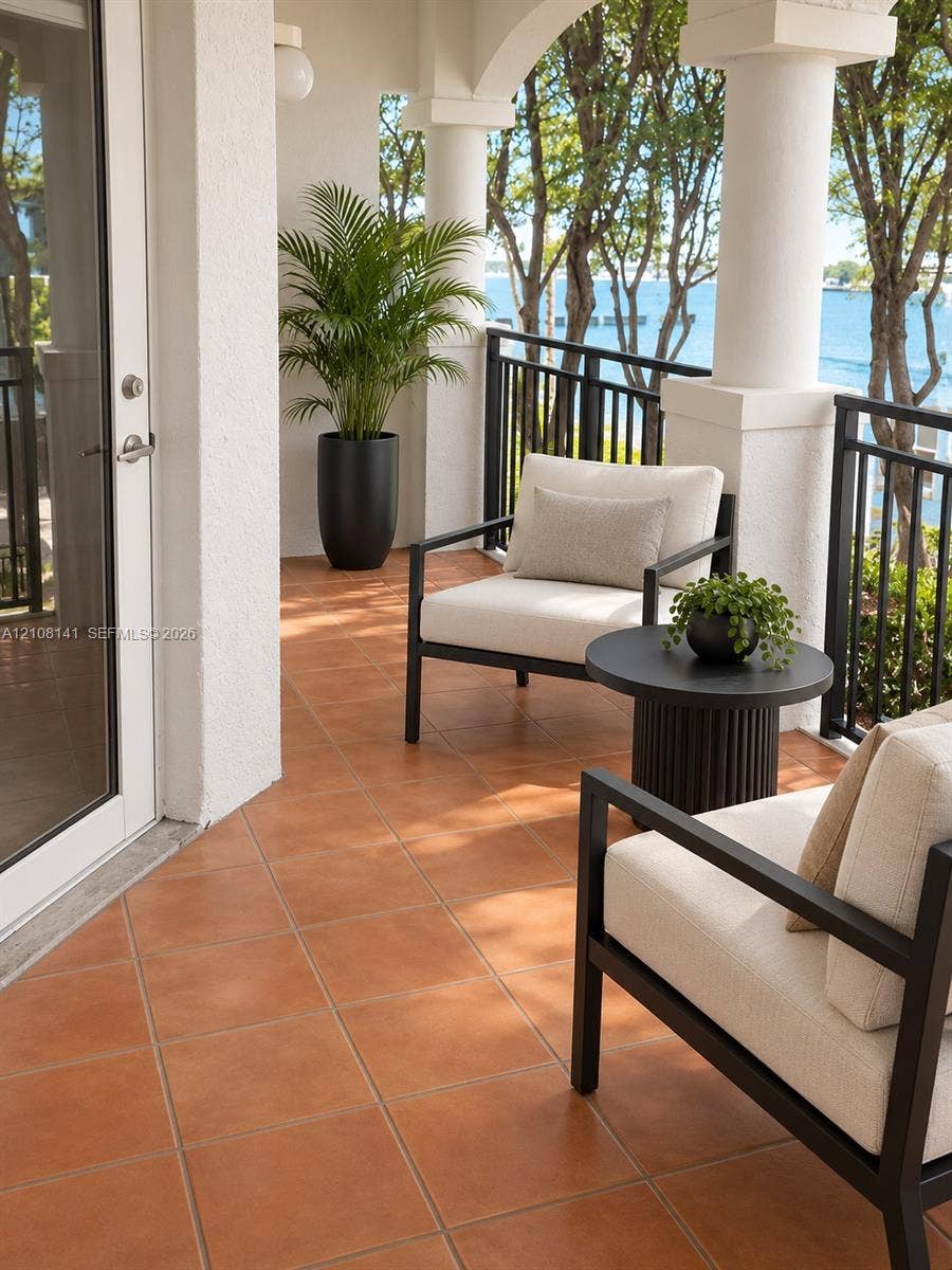 3135 NE 184th Street, #2205, Aventura, FL 33160 Covered balcony featuring terracotta-style tile flooring, decorative structural columns, and black metal railings with waterfront scenery