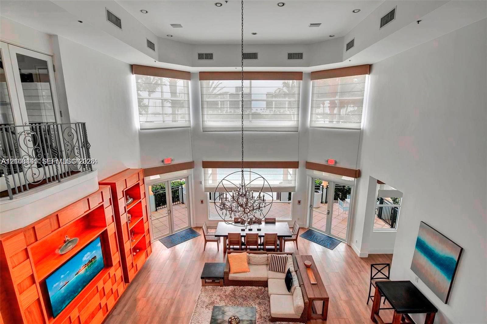 3135 NE 184th Street, #2205, Aventura, FL 33160 Double-height ceiling, floor-to-ceiling windows, custom built-in wood cabinetry, wood-finish flooring, and multi-tier spherical chandelier