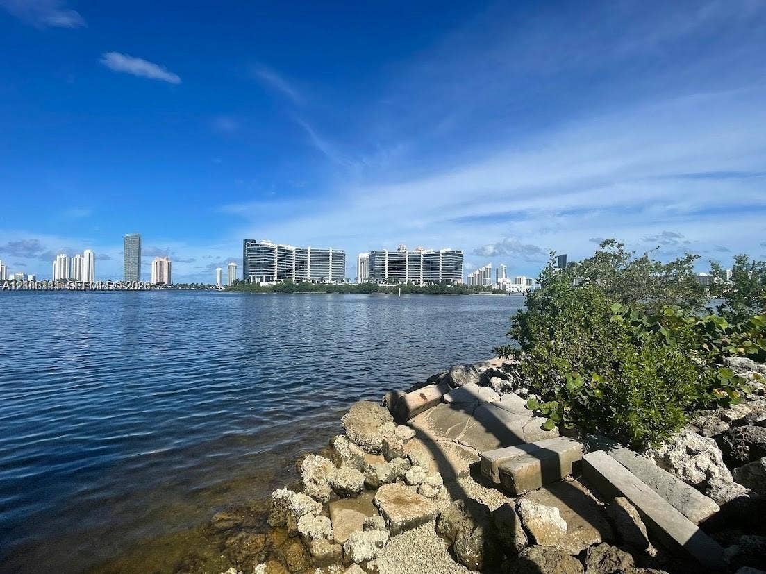 3135 NE 184th Street, #2205, Aventura, FL 33160 Waterfront property featuring a stone bulkhead, rocky shoreline, and native vegetation