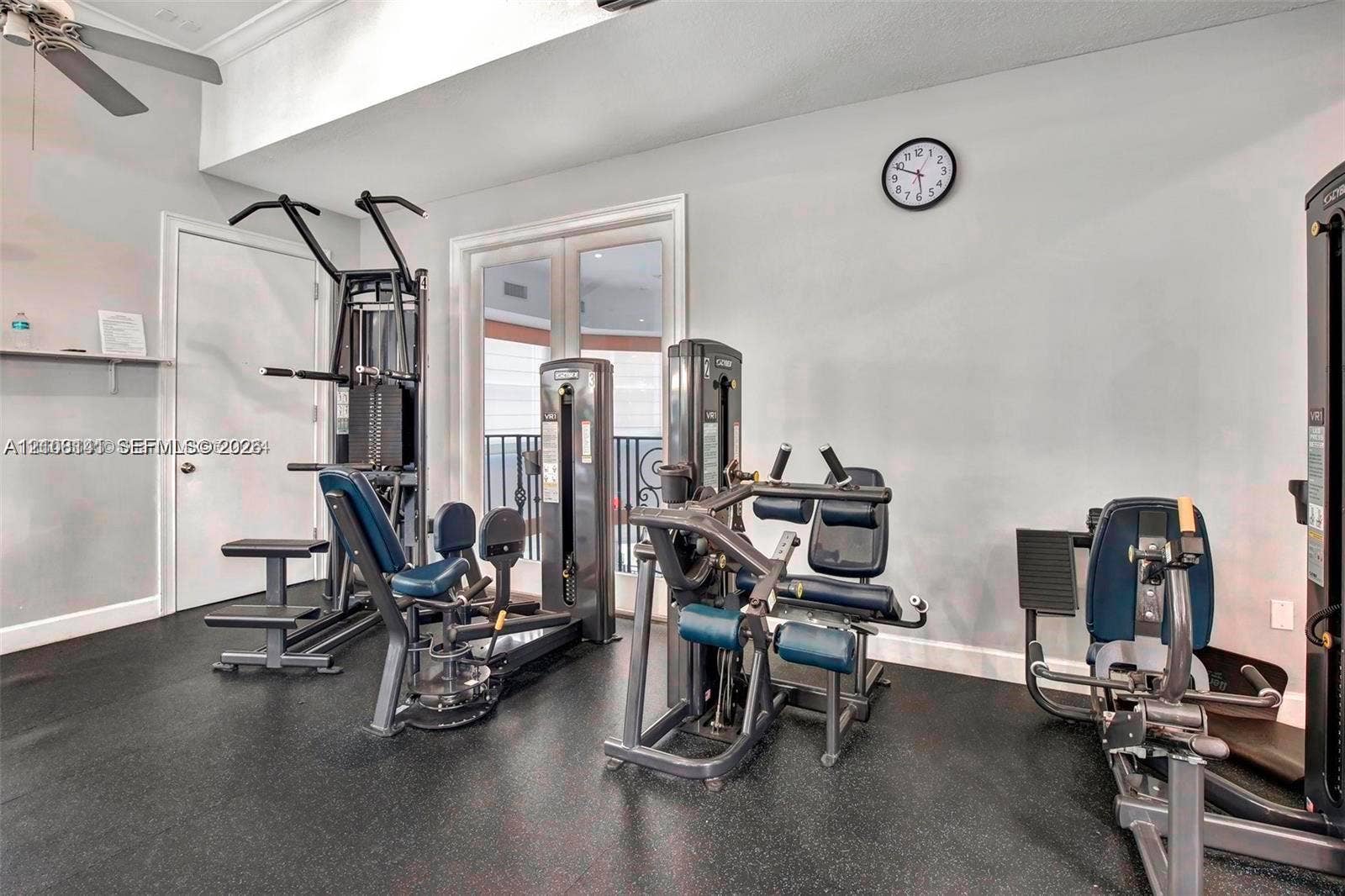 3135 NE 184th Street, #2205, Aventura, FL 33160 High ceiling featuring a flush-mount ceiling fan, double glass-panel doors with decorative metal railing, and resilient rubber-finish flooring