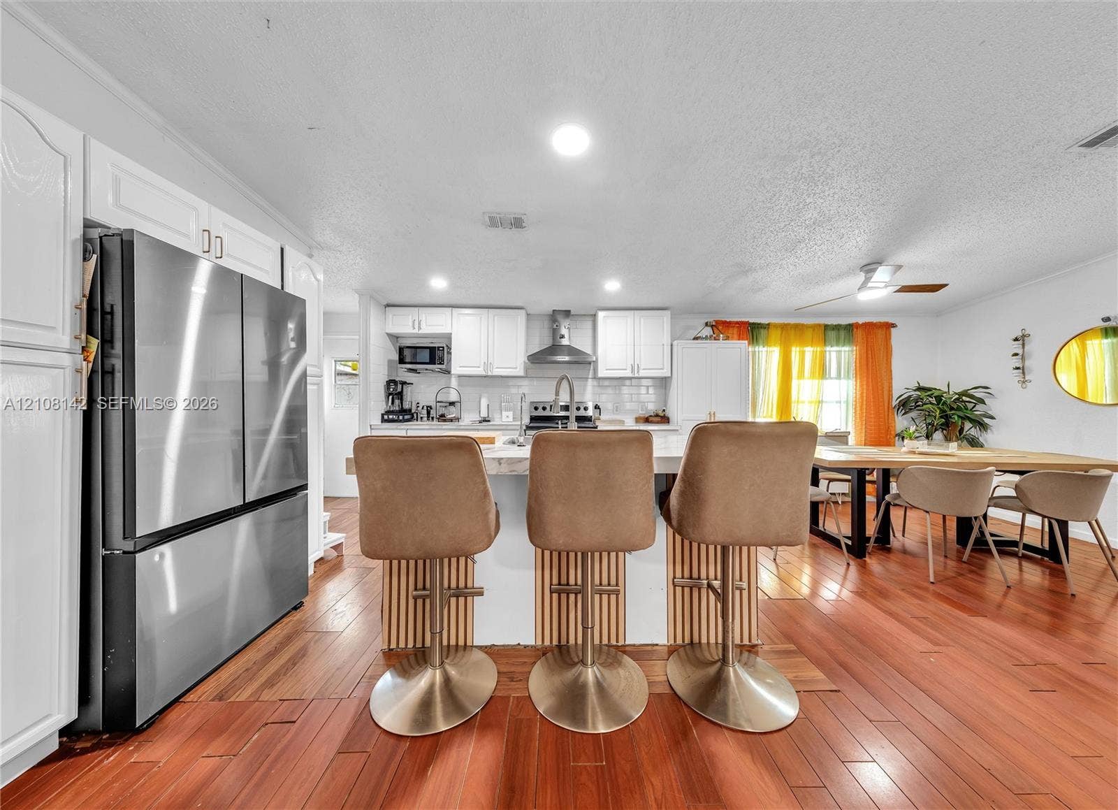 Kitchen featuring a central island with wood-slat detailing, white cabinetry, stainless steel appliances, and wood-finish flooring