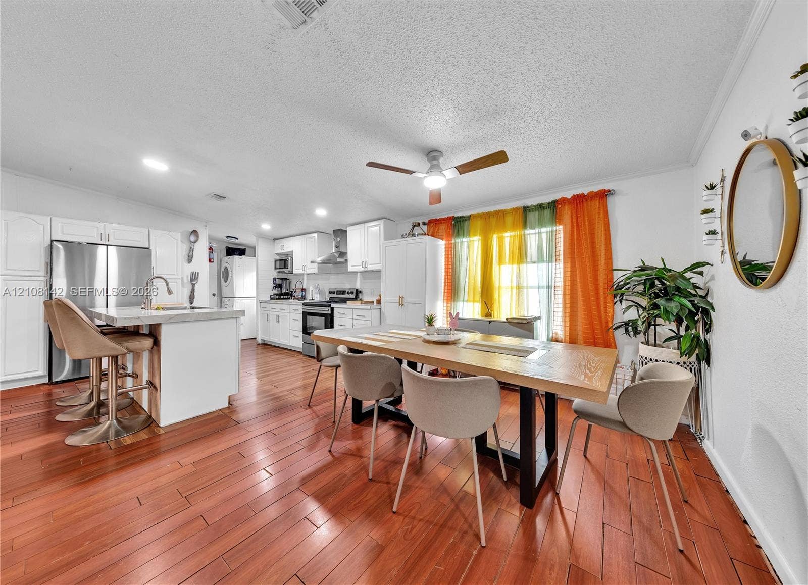 Kitchen featuring white cabinetry, an island with stone-composite countertop, stainless steel refrigerator, recessed lighting, and wood-finish flooring