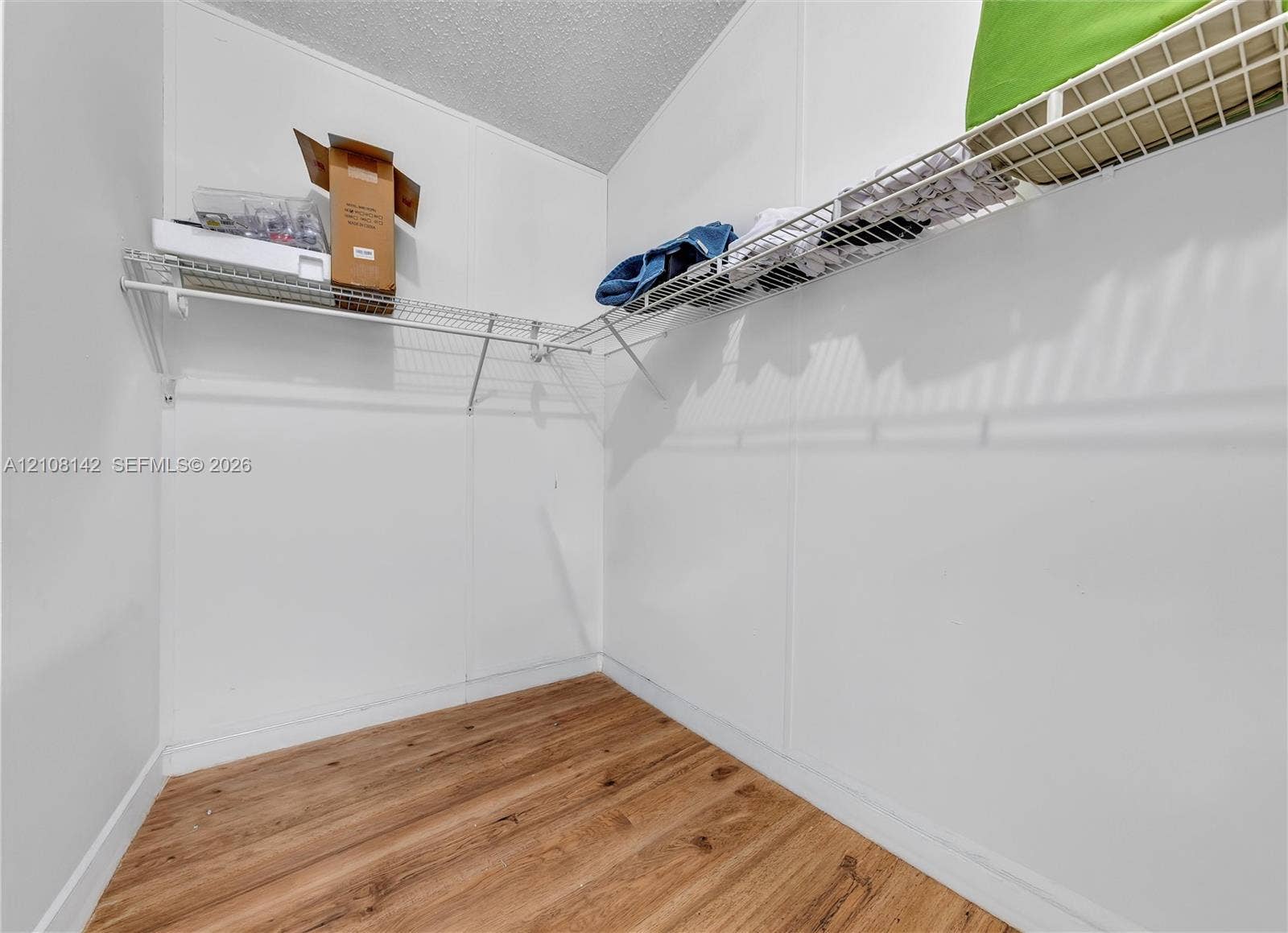 Storage area featuring wood-finish flooring and L-shaped white wire shelving