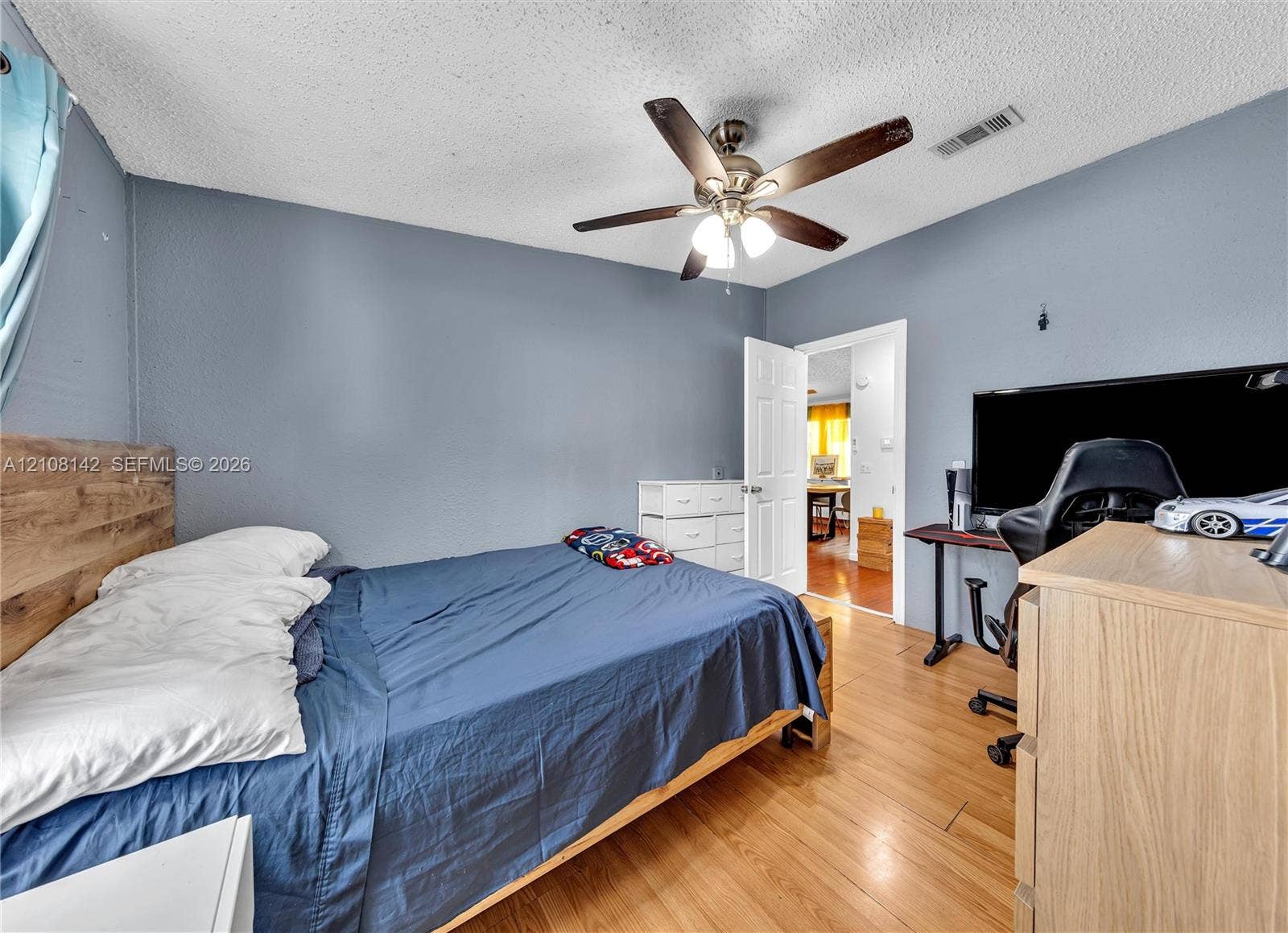 Wood-finish flooring, ceiling fan with integrated light fixture, and six-panel interior door