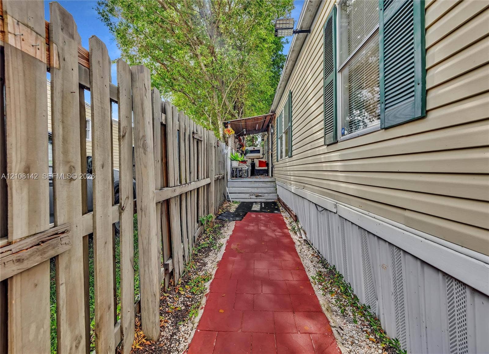 Vinyl siding exterior featuring decorative window shutters, a paved walkway, and a perimeter wood privacy fence