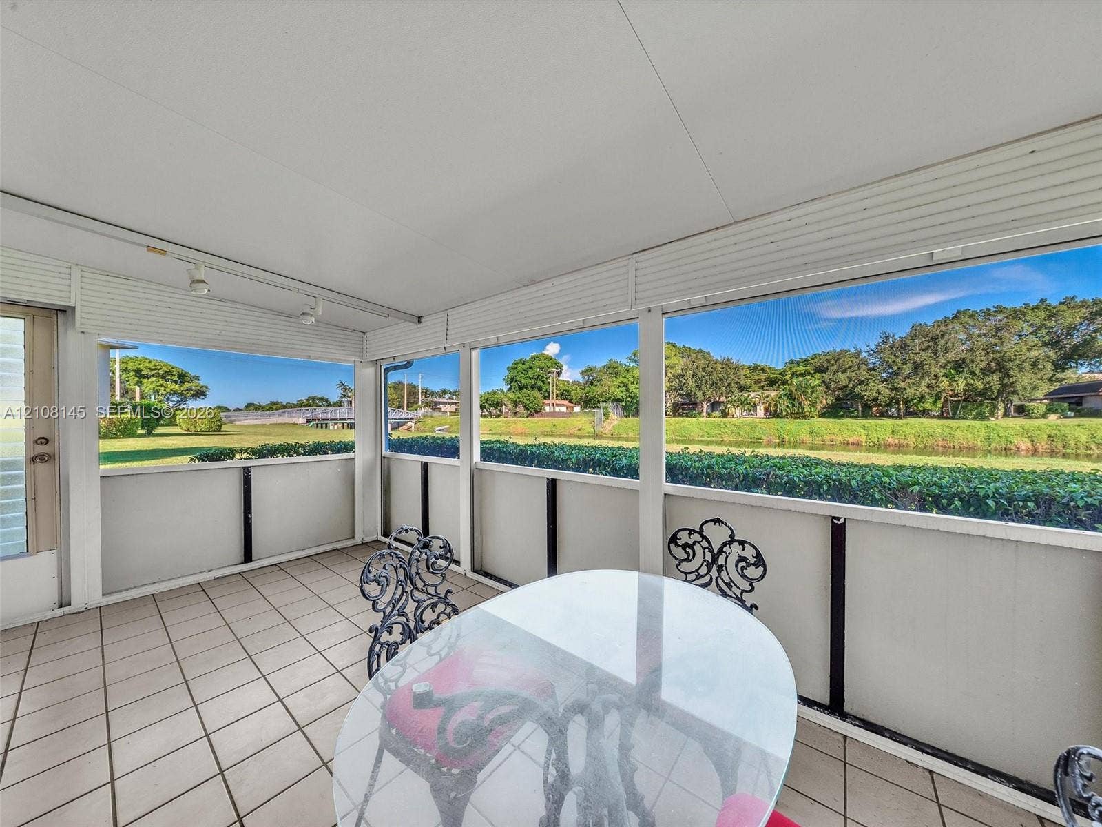 1020 Citrus Way, #101, Delray Beach, FL 33445 Enclosed patio featuring light-toned tile flooring, solid-surface lower wall panels, floor-to-ceiling screen windows, and track lighting