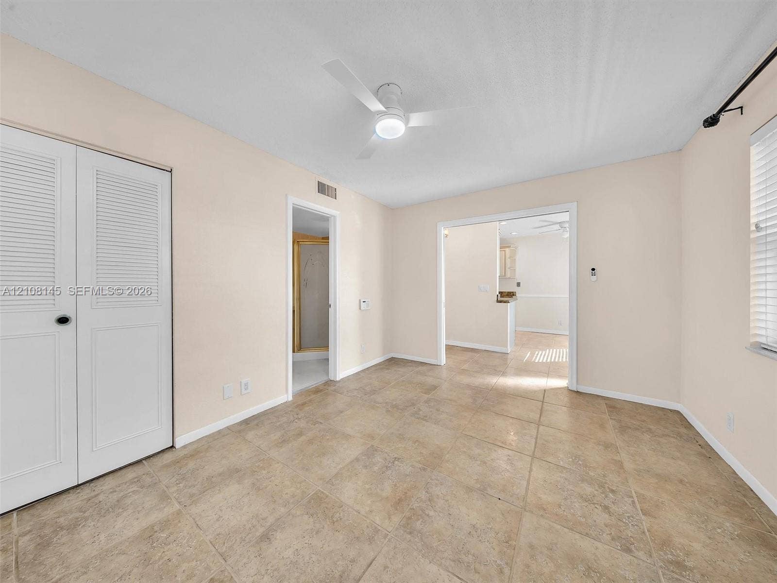 1020 Citrus Way, #101, Delray Beach, FL 33445 Interior space featuring large-format ceramic tile flooring, neutral wall tones, a ceiling-mounted light fixture with fan, and double-door closet storage