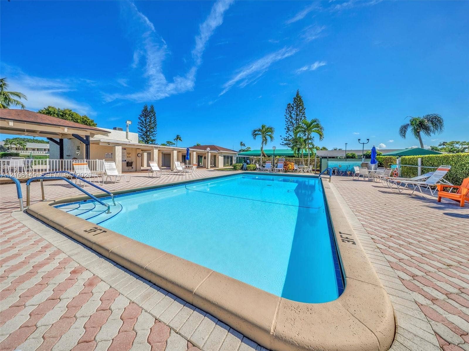 1020 Citrus Way, #101, Delray Beach, FL 33445 Inground swimming pool with built-in entry steps and metal handrails, surrounded by extensive brick-paver decking and a covered pavilion