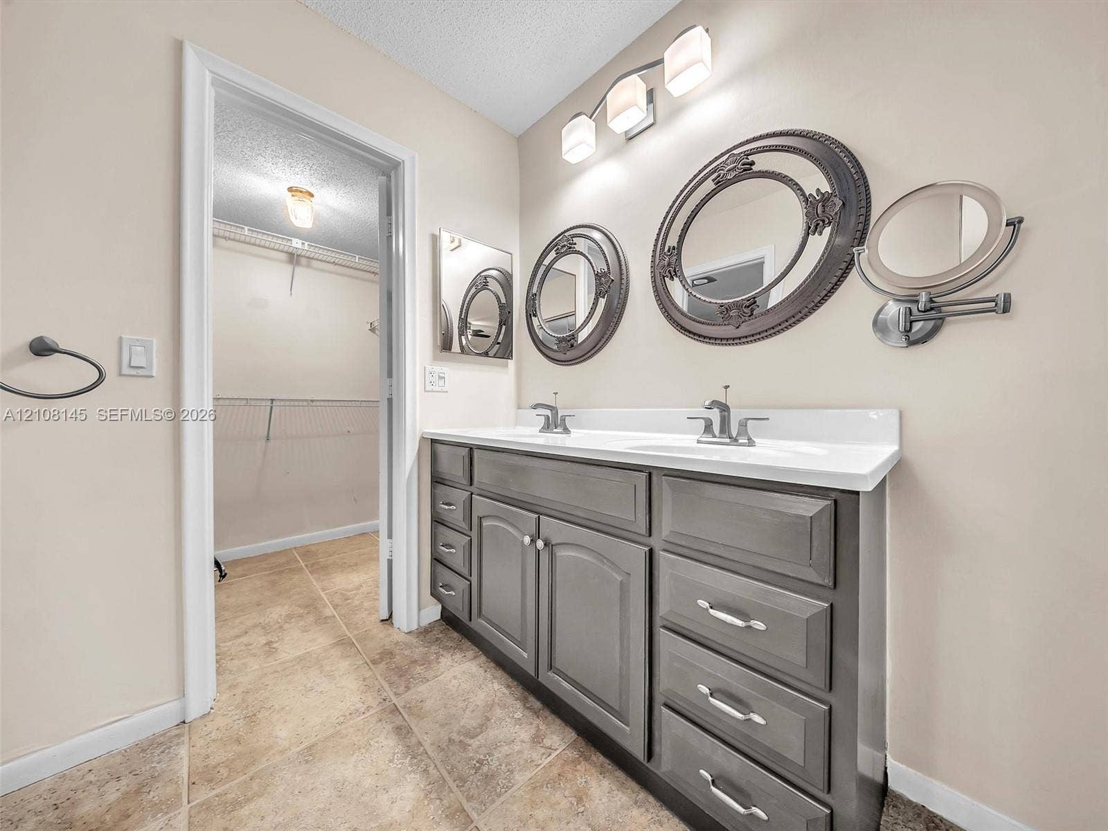 1020 Citrus Way, #101, Delray Beach, FL 33445 Dual-sink vanity with grey cabinetry, stone-finish countertop, tile flooring, and integrated three-light fixture