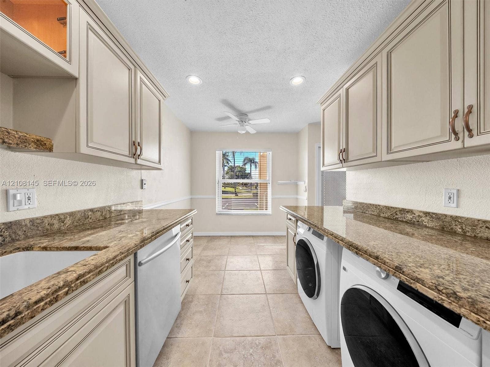 1020 Citrus Way, #101, Delray Beach, FL 33445 Laundry room featuring custom cabinetry, stone-finish countertops, tile flooring, recessed lighting, and a white basin sink