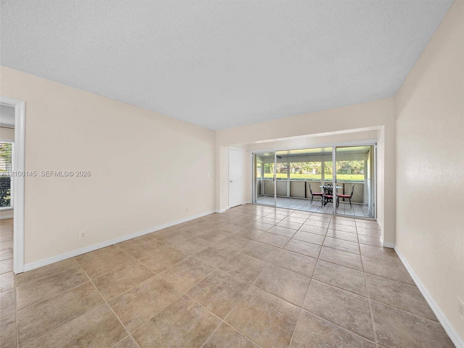 1020 Citrus Way, #101, Delray Beach, FL 33445 Neutral-toned interior featuring large-format ceramic tile flooring, sliding glass doors, and a screened-in lanai