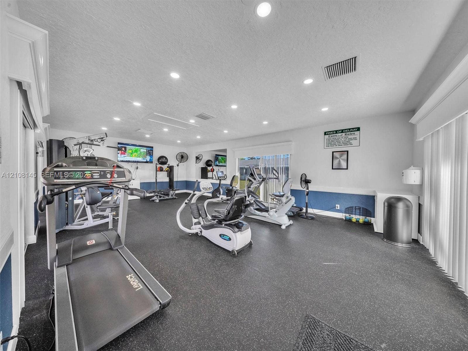 1020 Citrus Way, #101, Delray Beach, FL 33445 Fitness area featuring rubberized flooring, recessed ceiling lighting, wall-mounted mirrors, and vertical blinds