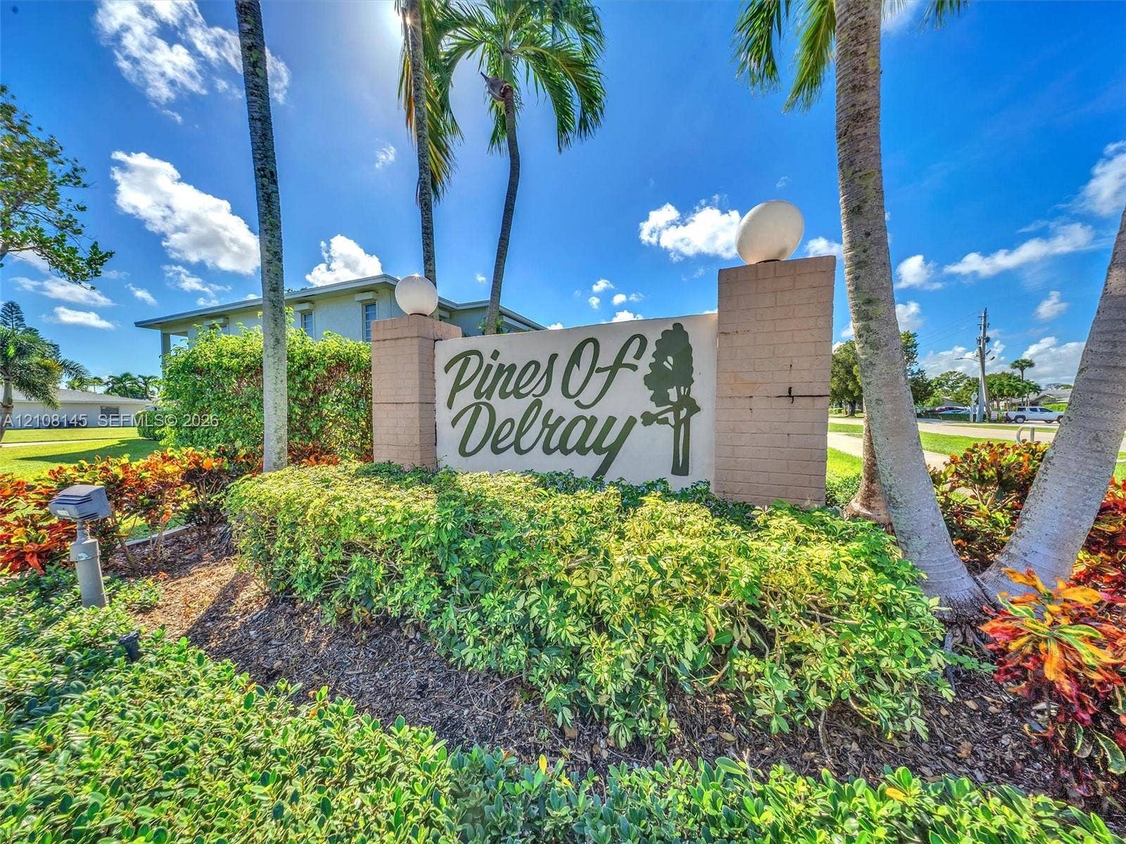 1020 Citrus Way, #101, Delray Beach, FL 33445 Community monument sign featuring masonry construction, spherical accent lighting, and manicured tropical landscaping with mature palm trees