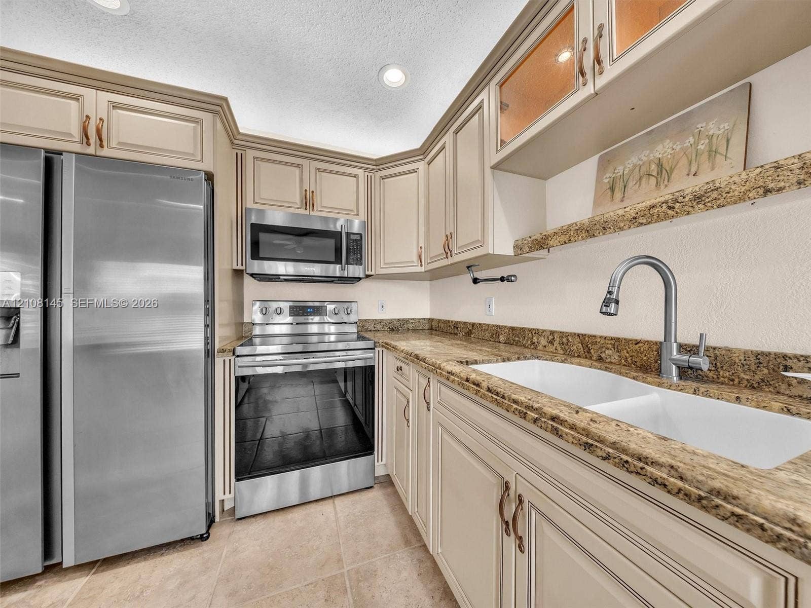 1020 Citrus Way, #101, Delray Beach, FL 33445 Kitchen featuring cream-colored shaker-style cabinetry, stone-finish countertops, stainless steel appliances, a dual-basin white sink with a pull-down faucet, and tile flooring