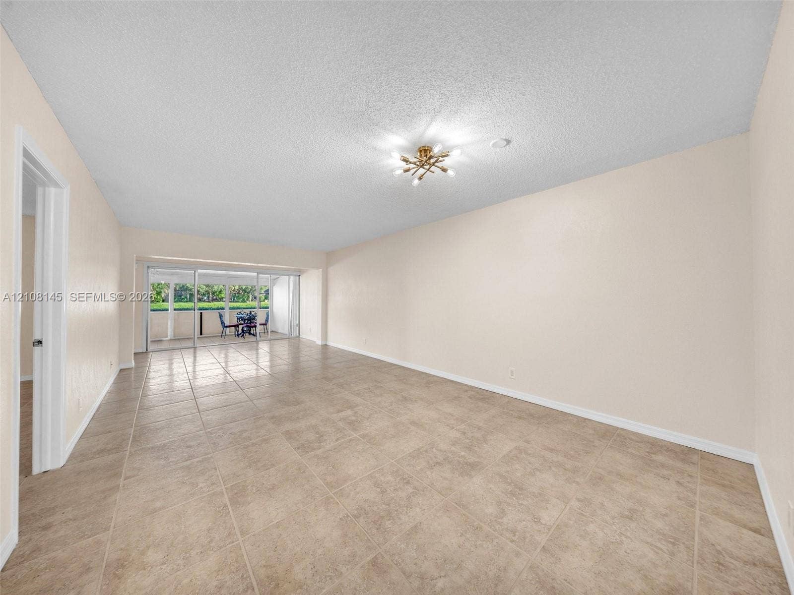 1020 Citrus Way, #101, Delray Beach, FL 33445 Open living space featuring large-format tile flooring, a multi-arm flush-mount light fixture, and floor-to-ceiling sliding glass doors
