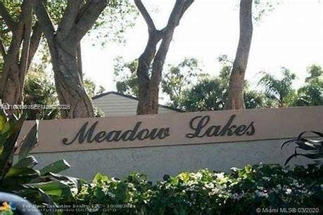 1258 S Military Trail, #813, Deerfield Beach, Deerfield Beach, FL 33442 Community entrance signage featuring dimensional lettering set against a stucco monument wall with mature trees and professional landscaping