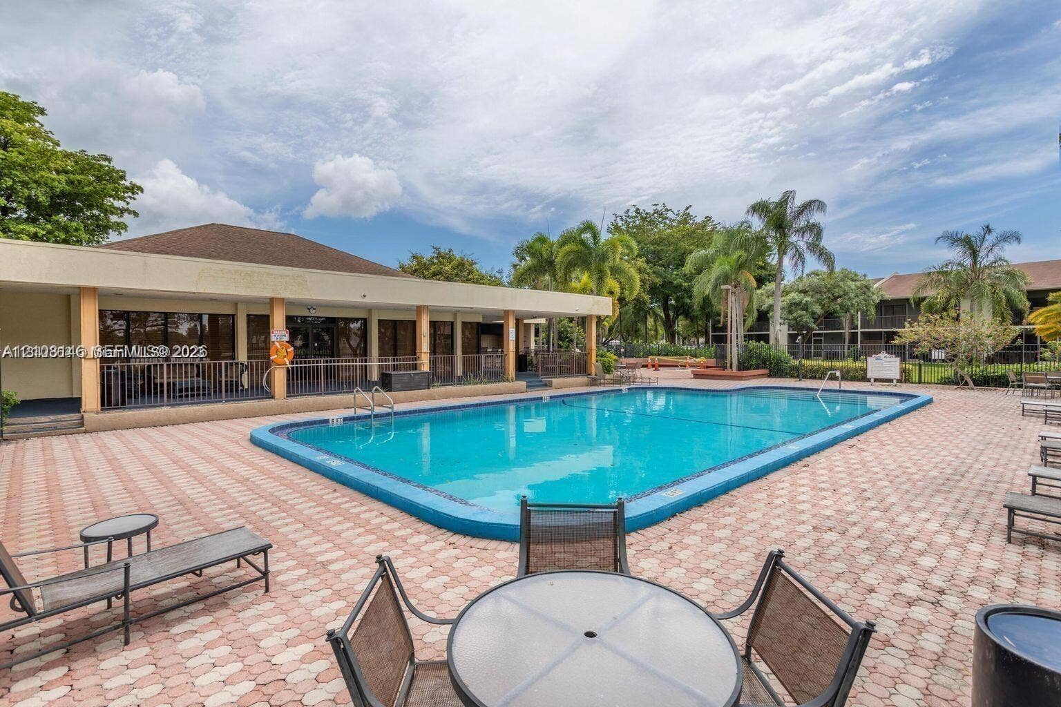 1258 S Military Trail, #813, Deerfield Beach, Deerfield Beach, FL 33442 In-ground swimming pool featuring a concrete deck with paver-style finish, covered patio space, and mature perimeter landscaping