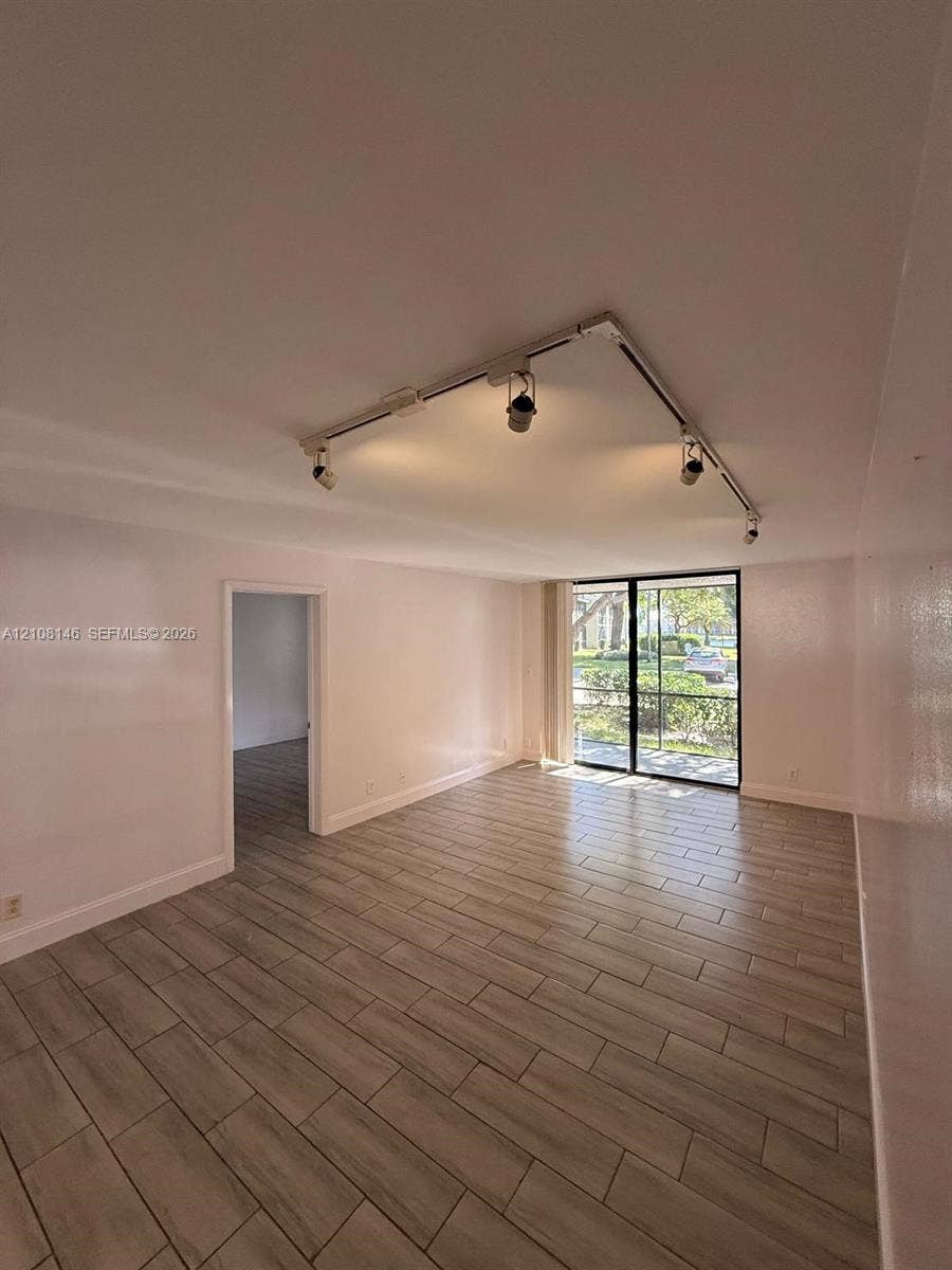 1258 S Military Trail, #813, Deerfield Beach, Deerfield Beach, FL 33442 Interior space featuring wood-finish tile flooring, ceiling-mounted track lighting, and sliding glass doors with screen enclosure
