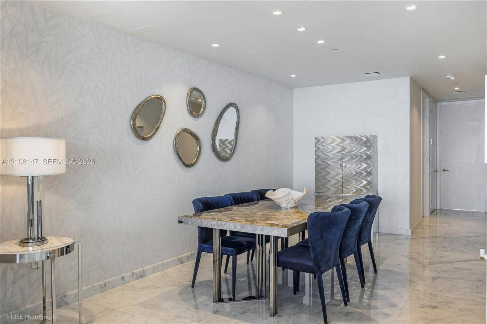 Interior space featuring polished stone flooring, textured wall covering, and recessed lighting throughout