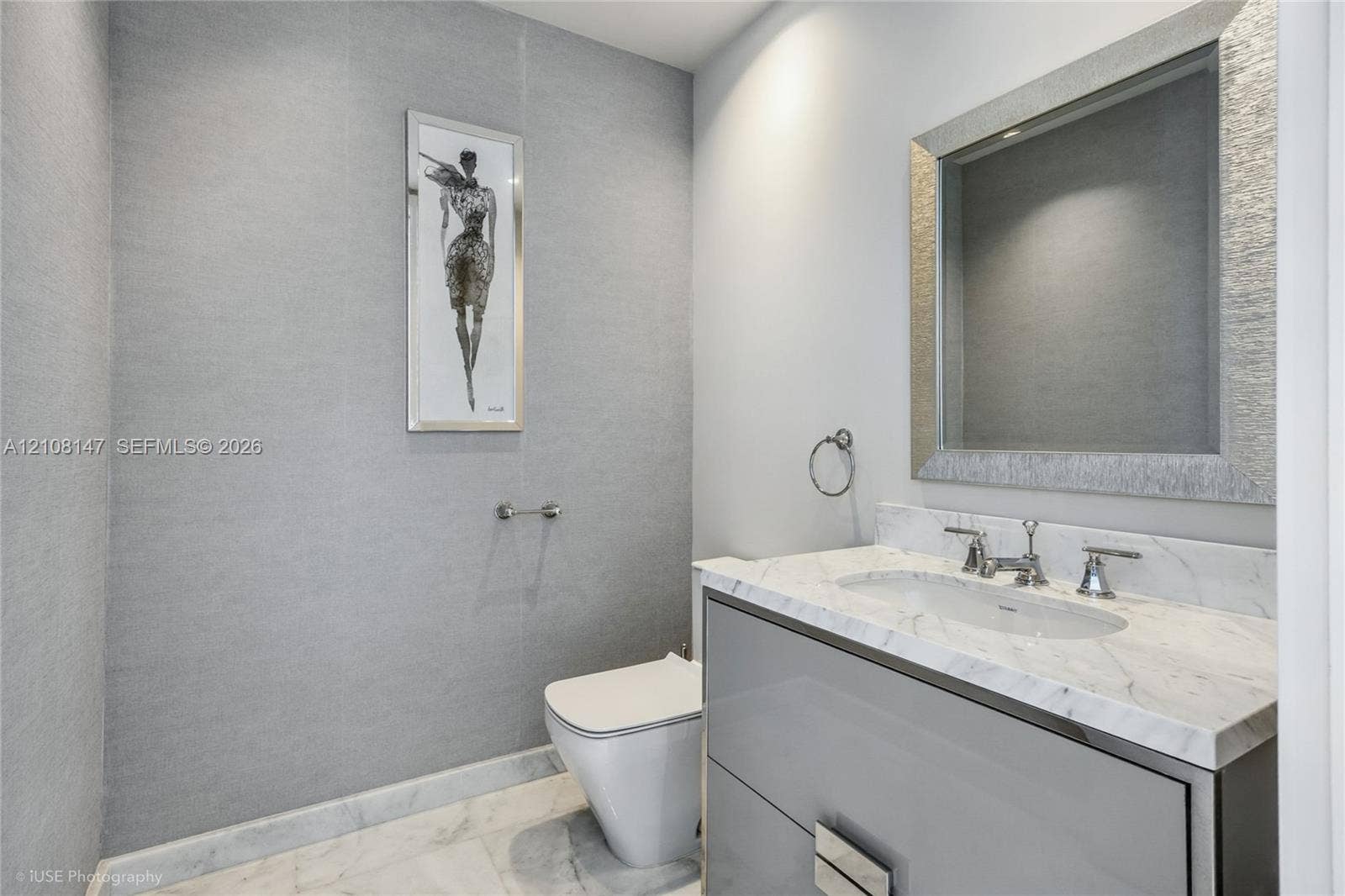 Wall-mounted vanity featuring high-gloss cabinetry, stone countertop with an integrated basin, polished chrome fixtures, and textured wall treatment