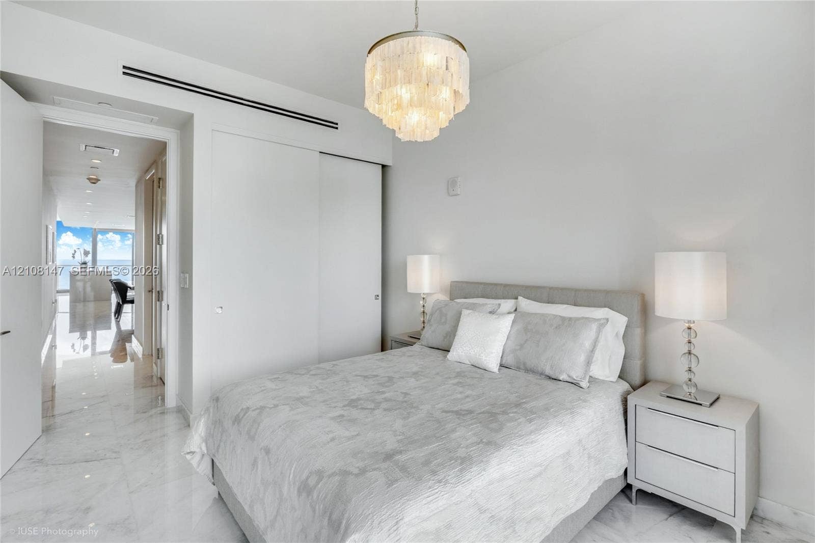 Multi-tiered crystal chandelier with a polished metal finish, polished stone-finish flooring, and built-in closet with sliding doors
