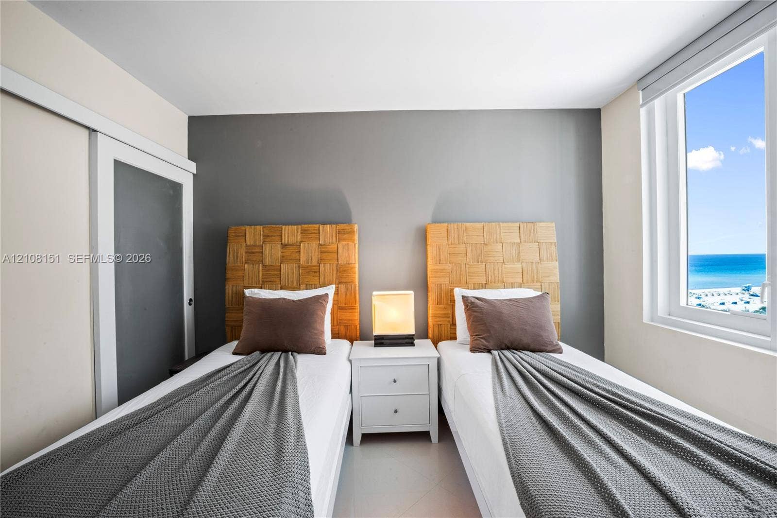 Room featuring a window with an ocean horizon, sliding door closet, and neutral-toned wall paint